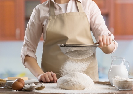 Woman sprinkling flour over fresh dough