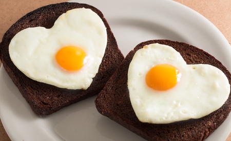 Two Slices of Bread with Fried Eggs in the Shape of Heart on the Plate