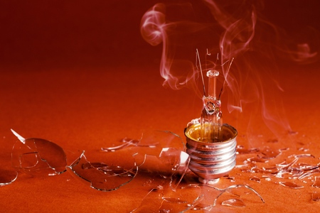 Burned Standard Incandescent Bulb with Smoke on Red Background