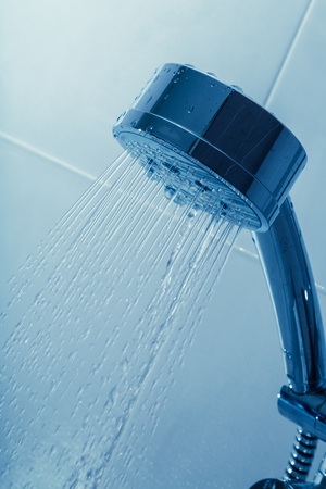 Shower Head with Water Stream on Blue Backgroundの写真素材