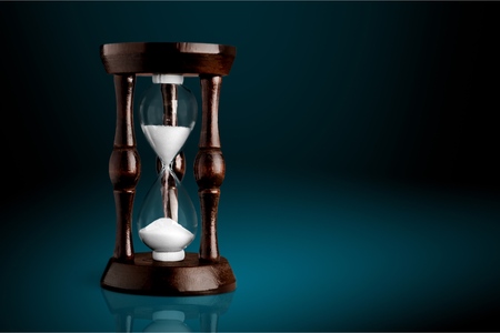 Sand running in hourglass on light background