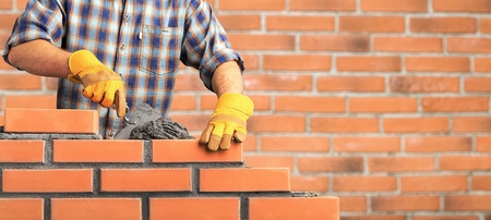 Bricklayer industrial worker installing brick masonry