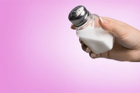 Close up of hand holding white salt cellar