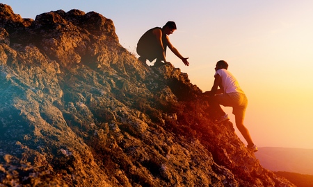 People helping each other hike on the mountainの写真素材