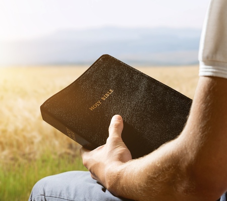 Man reading old Bible book on background