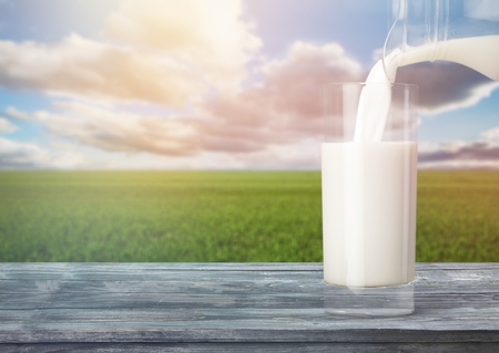 Glass jug of fresh milk on backgroundの写真素材