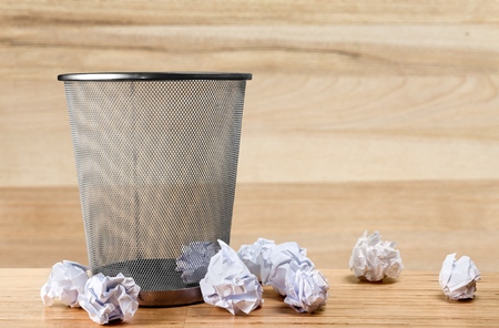 Trash can with paper sheets on wooden deskの写真素材