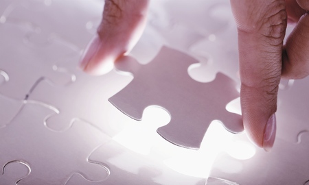 Fitting last white puzzle piece. Concept image of building and button up.