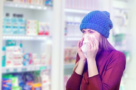 Young woman in hat sneezingの写真素材