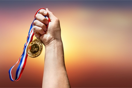 Gold medal with ribbon in hand