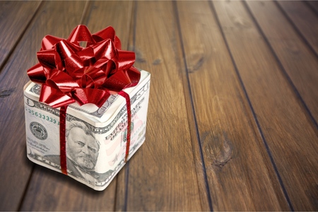 Christmas present with red bow wrapped in dollar banknotes isolated on white backgroundの写真素材