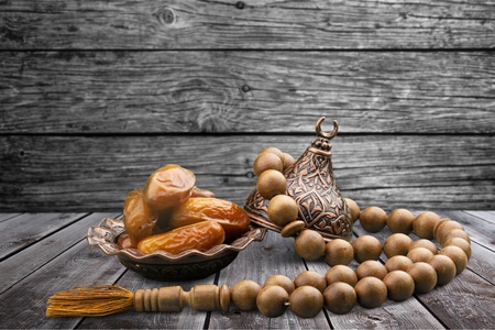 Date fruits in an ornamental bowl with prayer beads.の写真素材