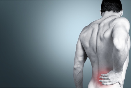 Back view of shirtless man touching his aching back