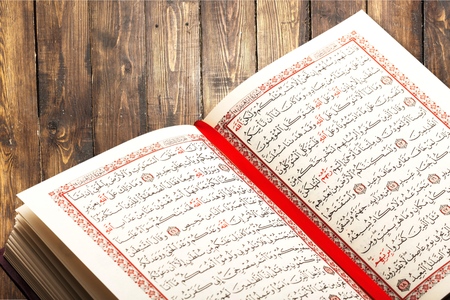 Opened Quran on Muslim prayer mat indoors