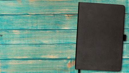 A black notebook on a wooden backgroundの写真素材