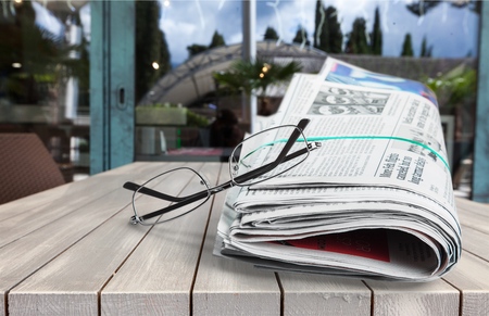 Newspaper and Reading Glasses on wooden table