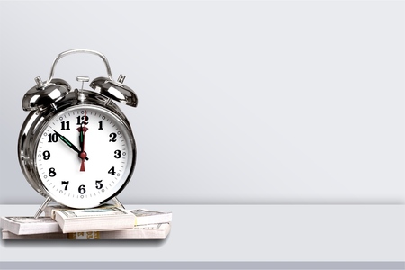 Alarm clock on dollar bills on a table