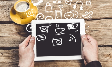 Hands holding digital tablet computer with isolated on wooden tableの写真素材