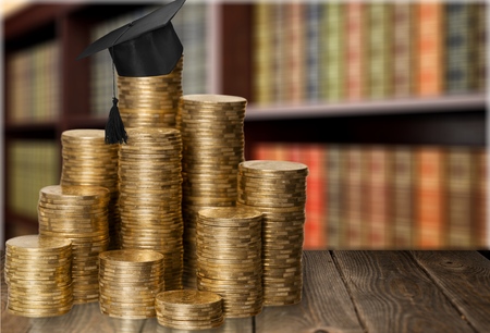 A graduation hat on top of stacks of coinsの写真素材