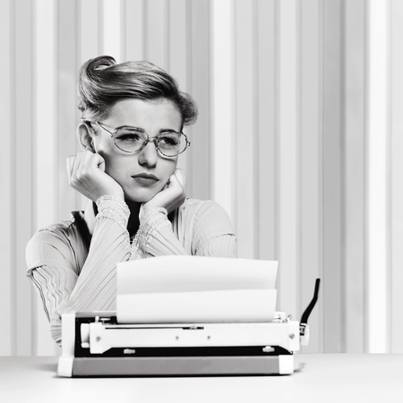 Attractive young woman sitting in front of a vintage typewriter