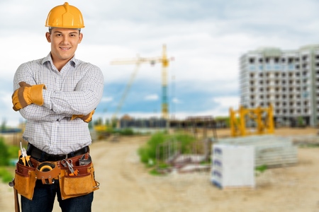 A worker with a tool belt on a construction site background