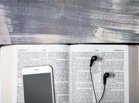 Contemporary image of a Bible with headphones and mobile phone.の写真素材