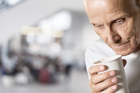 Thoughtful senior man holding white cupの写真素材