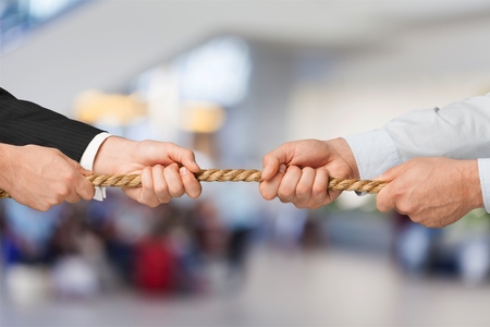 Business people pulling rope in opposite directionsの写真素材