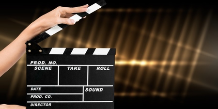 Cinema clapperboard in female hands on blueの写真素材