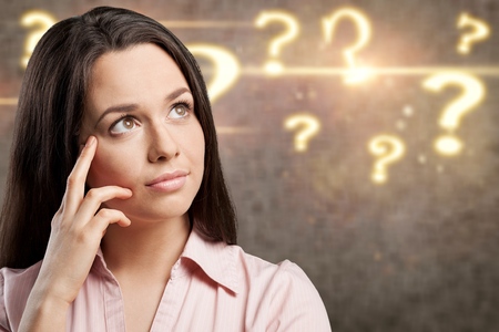 Thoughtful young businesswoman with question marks in