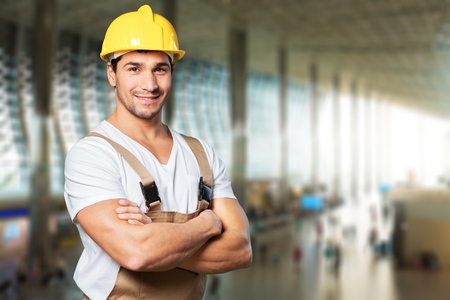 Young builder in hardhat on blurred construction Young builder in hardhat on blurred construction