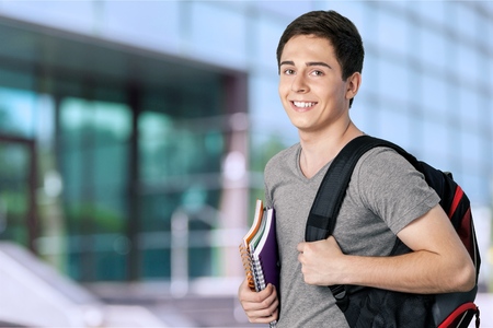 Smiling handsome boy with books on  backgroundの写真素材