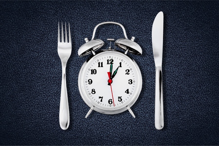 Alarm clock with knife and fork  for mealtime or diet conceptの写真素材