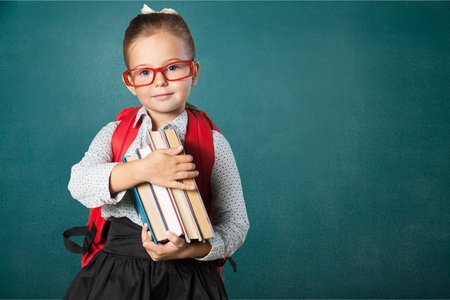 Cute little schoolgirl in glasses on blackboardの写真素材