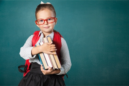 Cute little schoolgirl in glasses on blackboard