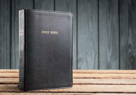 holy bible with eye glasses and note book, pencil   on wooden table with window light in the morning, copy spaceの写真素材