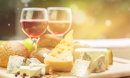 Assortment of cheese on board and two glasses of wineの写真素材