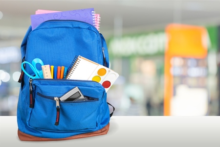 School Backpack with stationery on wooden table