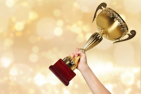 Hands holding golden trophy on light backgroundの写真素材