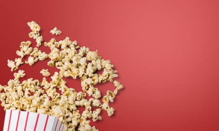 Spilled popcorn on a red background, cinema, movies and entertainment conceptの写真素材