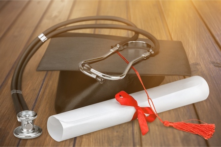 Graduation hat with  tassel, diploma with red ribbon and  stethoscope showing someone who just graduated from medical school.の写真素材