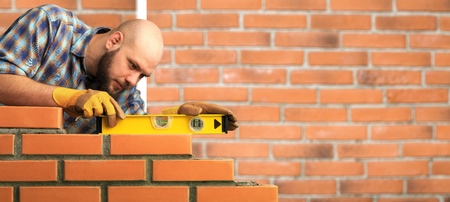 Bricklayer industrial worker installing brick masonryの写真素材
