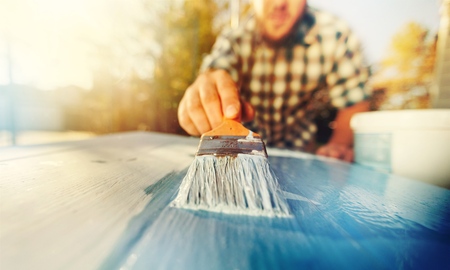 Man with paintbrush in hand and painting on the wooden boardの写真素材
