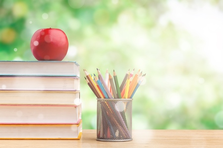 Back to school background with books and apple over blackboard
