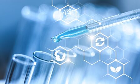 In a futuristic laboratory, a scientist with a pipette analyzes a colored liquid to extract the DNA and molecules in the test tubes.Concept:research,biochemistry,immersive technology,augmented realityの写真素材