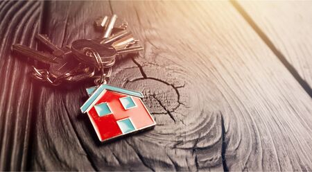 House keys with trinket on wooden background