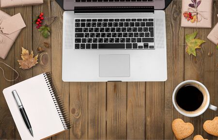 Hello Autumn flat lay background. Top view of workspace or office desk with laptop, tea or coffee cup, maple leaves, vintage book and honey biscuits and cookies. lish office desk.の写真素材