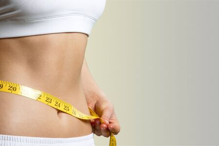 Slim young woman measuring her thin waist