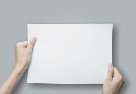 Close up hands holding blank paper for work at desk office top view. clipping path, Isolated.
    
 ...