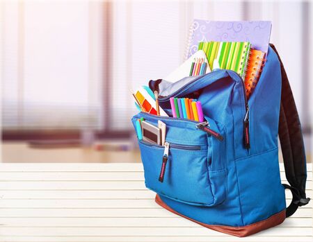 Colorful school supplies  in backpack on blackboard backgroundの写真素材
